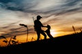 Silhouettes of a girl with a rifle and her dog,behind them is a beautiful sunset.