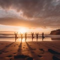 Silhouettes of girls doing yoga on the sand of a sunset beach with surf and sun Royalty Free Stock Photo