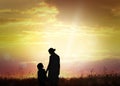 Silhouettes of godparent with child in field at sunrise Royalty Free Stock Photo