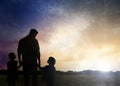 Silhouettes of godparent with children in field at sunrise