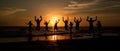 Silhouettes of a group of people on the beach, joyfully jumping up against the backdrop of the setting sun. The scene is Royalty Free Stock Photo