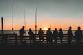 Silhouettes Of A Group Of People On A Pier, Enjoying The Beautiful Sunset