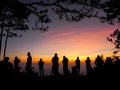 Silhouettes of a group of people standing together in line in the early morning