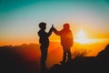 Silhouettes of happy boy and girl hiking at sunset mountains Royalty Free Stock Photo