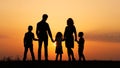 Silhouettes of happy family holding the hands in the meadow during sunset. Royalty Free Stock Photo