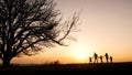 Silhouettes of happy family walking together in the meadow during sunset Royalty Free Stock Photo