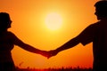 Silhouettes of happy smiling young couple in summer wheat field