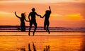 Silhouettes of happy young friends jumping on the