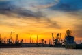 Silhouettes of harbor cranes and cargo ships in sea port on the background of sunset Royalty Free Stock Photo