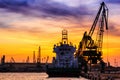 Silhouettes of harbor cranes and cargo ships in the seaport of Varna at sunset Royalty Free Stock Photo