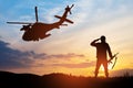 Silhouettes of helicopter and soldier on background of sunset. Royalty Free Stock Photo