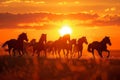 Silhouettes of herd of horses galloping across field at sunset