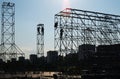 Silhouettes of high-rise assemblers on a metal truss against the background of a blue sky and the city