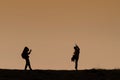 Silhouettes of hikers with backpacks enjoying sunset view from top of a mountain Royalty Free Stock Photo