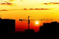 Silhouettes of houses and construction crane against setting sun, city skyline at sunset Royalty Free Stock Photo