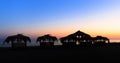 Silhouettes of hovels with the roofs covered with palm leaves for rest on the beach at sunset Royalty Free Stock Photo