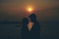 Silhouettes of hugging couple against the sea at sunset.