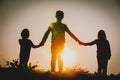 Silhouettes of kids - boy and girls - holding hands at sunset Royalty Free Stock Photo