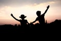 Silhouettes of kids jumping off a cliff at sunset