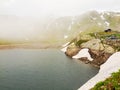 Silhouettes of lake banks in Alpine mountains, heavy dark clouds of mist are coming with strong wind.