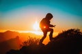 Silhouettes of little girl hiking at sunset mountains