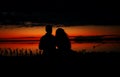 Silhouettes of lovers couple hugging at sunset, sunrise against the backdrop of the sea, sun, clouds in fiery red, orange colors Royalty Free Stock Photo