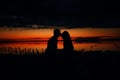 Silhouettes of lovers couple hugging at sunset, sunrise against the backdrop of the sea, sun, clouds in fiery red, orange colors Royalty Free Stock Photo