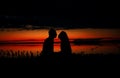 Silhouettes of lovers couple hugging at sunset, sunrise against the backdrop of the sea, sun, clouds in fiery red, orange colors Royalty Free Stock Photo