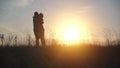 Silhouettes of lovers run to meet each other against the background of sunset.