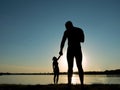 Silhouettes of a loving couple on the beach. Sunset on the beach. Giant and baby Royalty Free Stock Photo
