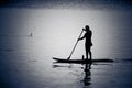 Silhouettes of man canoeing in calm water