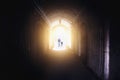 Silhouettes of man and child, father and daughter, walking into light from dark tunnel Royalty Free Stock Photo