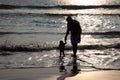 Silhouettes of man and kids play in the waves in the Bekal beach