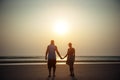 Silhouettes of man and woman on the background of the sea in the rays of setting sun. Young couple in love holding hands at sunset Royalty Free Stock Photo
