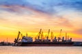 Silhouettes of mechanical cranes and industrial cargo ships in sea port on the background of sunset Royalty Free Stock Photo