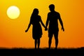 Silhouettes of men and women standing and holding hands at sunset.