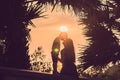 Silhouettes of mother and son, who meet the sunset in the tropics against the backdrop of palm trees Royalty Free Stock Photo