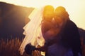 The silhouettes of newlyweds standing on the field in the sunny