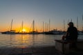 Silhouettes of people admiring the sunrise and yacht masts all back-lit by golden glow Royalty Free Stock Photo