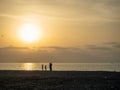 Silhouettes of people against the backdrop of a bright sunset. Orange sunset. Family on vacation. Sea Royalty Free Stock Photo