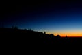 Silhouettes of people ant tents in the mountains at sunset light