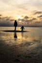 Silhouettes of unrecognizable people on the beach at sunset