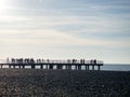 Silhouettes of people on the bridge on the seashore. People see off the sunset. Sea coast. Pier on the sea Royalty Free Stock Photo