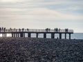 Silhouettes of people on the bridge on the seashore. People see off the sunset. Sea coast. Pier on the sea Royalty Free Stock Photo