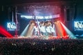 Silhouettes of people in a bright in the pop rock concert in front of the stage. Hands with gesture Horns. That rocks. Party in a