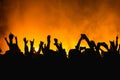 Silhouettes of concert crowd in front of bright stage lights. Dancing people with hands on against stage light. Fans burn yellow Royalty Free Stock Photo