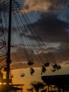 Silhouettes of people on the carousel. Concept of fun and entertainment. People on carousels at sunset. Resort town. Adrenalin.