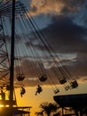 Silhouettes of people on the carousel. Concept of fun and entertainment. People on carousels at sunset. Resort town. Lunapark.