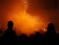 Silhouettes of people and a child on his father\'s shoulders watching the pyrotechnic show of the devils