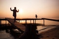 Silhouettes of people children on shore lake. Summer sunset on water. evening walk outdoor on bridge Royalty Free Stock Photo